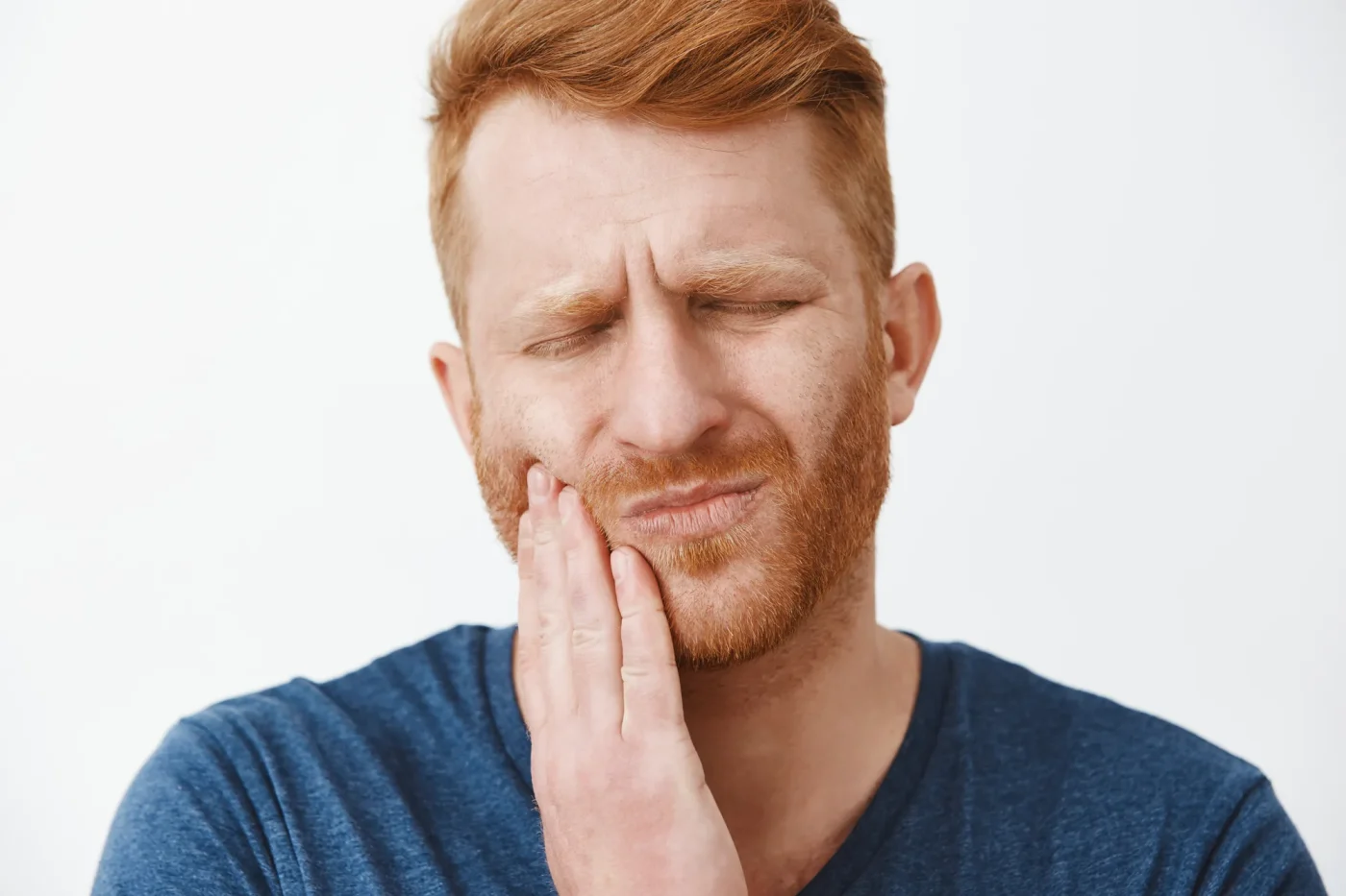 Man holding his cheek with a toothache, in need of an emergency dentist